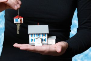 woman holding miniature house and key